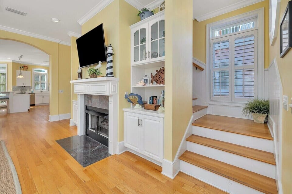 Living room with fireplace, built-ins, flat-screen TV, and staircase