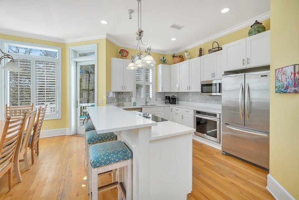 Kitchen with white island, pendant lights, and stainless appliances