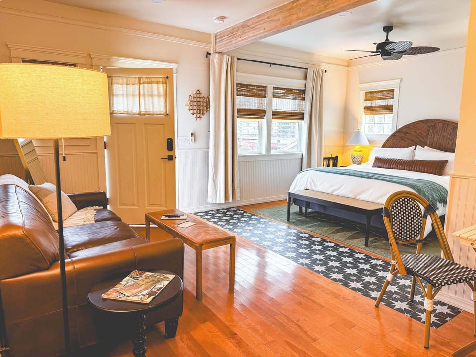 Open-plan living space combining a leather couch, coffee table, and king bed area.