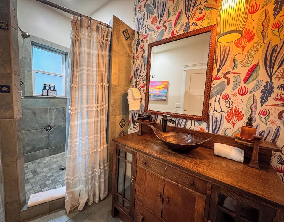 Stylish bathroom with a copper vessel sink, rustic wooden vanity, and tiled shower.