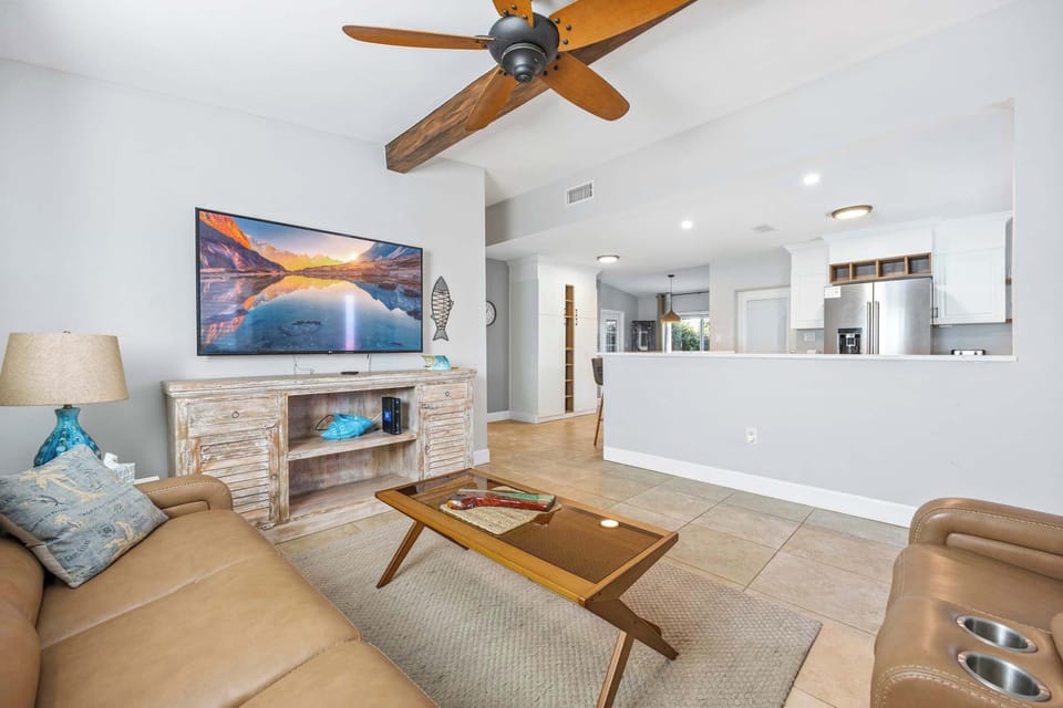 Open living area with leather seating and a large wall-mounted television