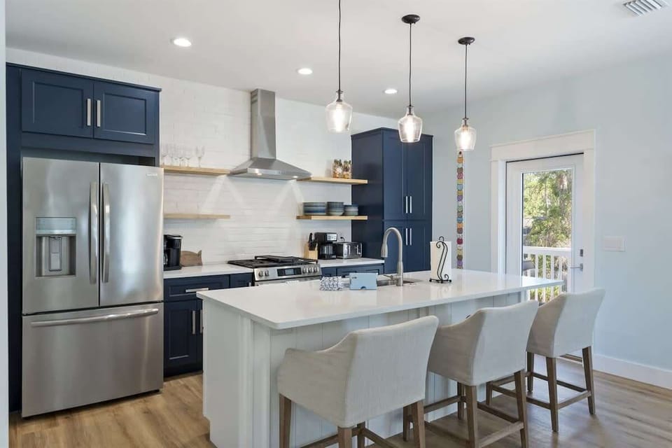 - Fully equipped chef’s kitchen with stainless steel appliances, navy cabinets, and a stove - Stylish pendant lights over a spacious island with plush seating for morning chats - Welcoming and functional space perfect for any meal or occasion