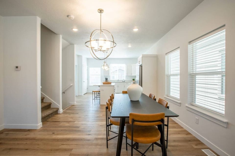 Dine beneath a statement chandelier that adds mid-century elegance to the bright, open-concept layout — perfect for casual breakfasts or family dinners.