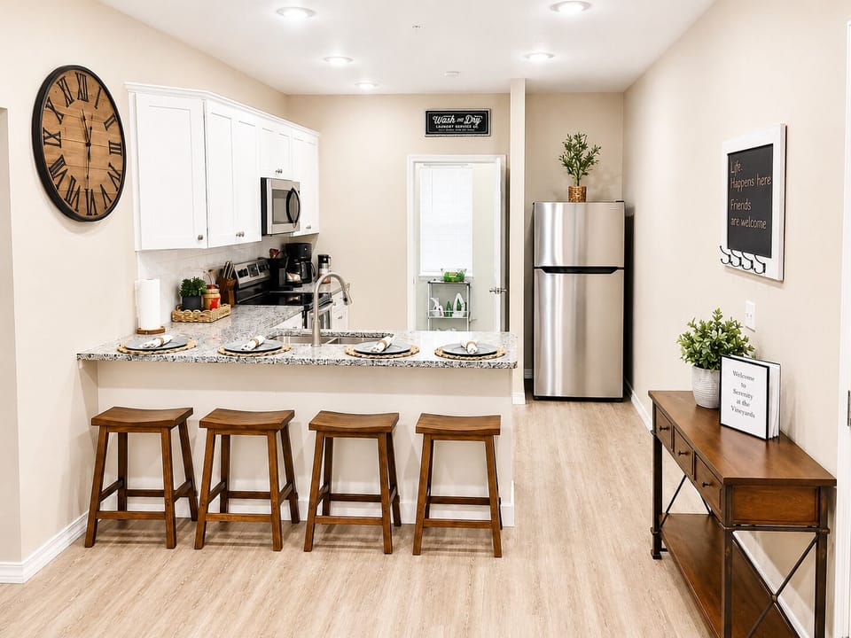 Kitchen with four barstools full-size fridge attached to laundry room