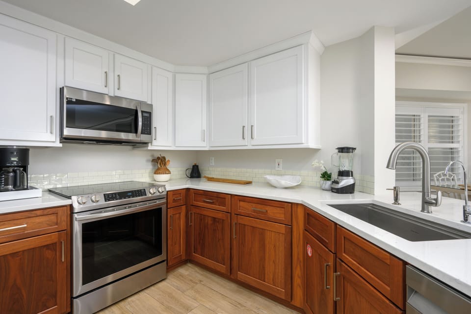 Crisp white cabinetry, stainless steel appliances, and a double-basin sink create a clean, functional workspace.