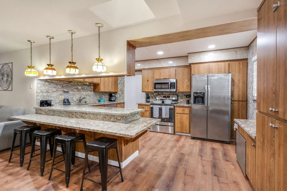 fully equipped kitchen, featuring stainless steel appliances, granite countertops, and a cozy breakfast bar.