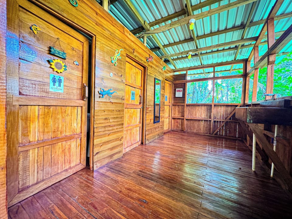The outdoor bathhouse by the pool has three private stalls, each with a shower, toilet, and sink.