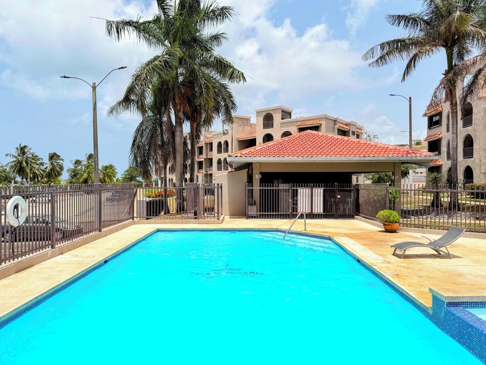 Sunny resort-style pool with palm trees and shaded lounge pavilion