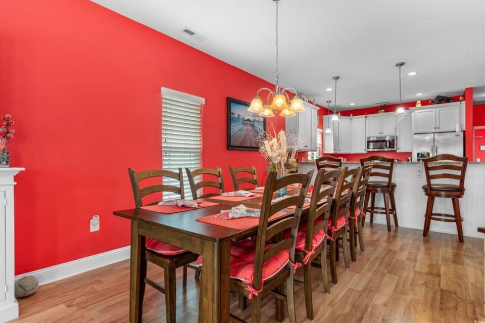 Dining room with 8 chairs and 4 stools in kitchen counter.