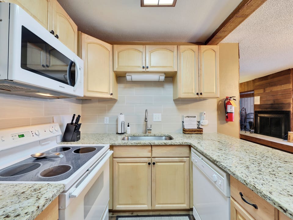 Fully stocked kitchen with stone countertops, a tile backsplash, and all the amenities needed to prepare meals after a day on the slopes