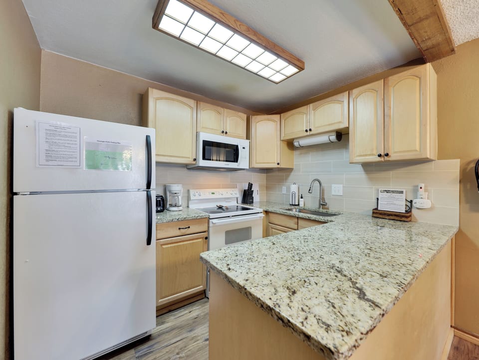 Fully stocked kitchen with stone countertops, a tile backsplash, and all the amenities needed to prepare meals after a day on the slopes