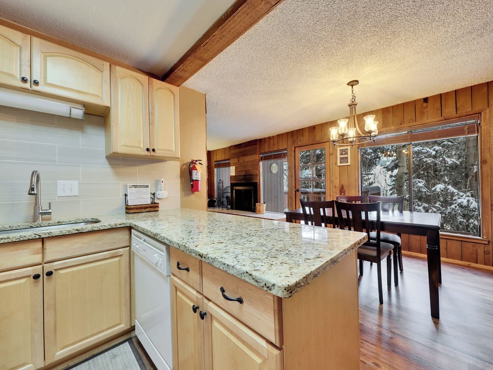 Fully stocked kitchen with stone countertops, a tile backsplash, and all the amenities needed to prepare meals after a day on the slopes
