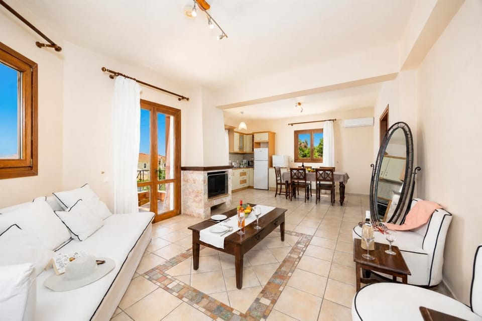 Open-plan living room with sofa, dining area, kitchen, ornamental fireplace, A/C, WiFi internet, and satellite TV