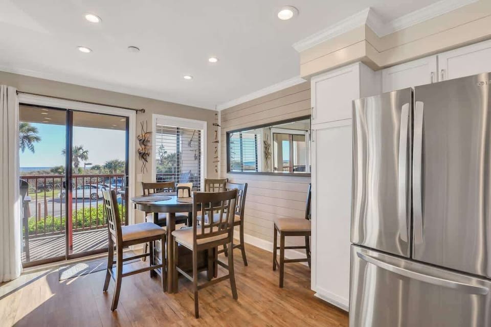 A high-top wooden dining set sits adjacent to the balcony.
