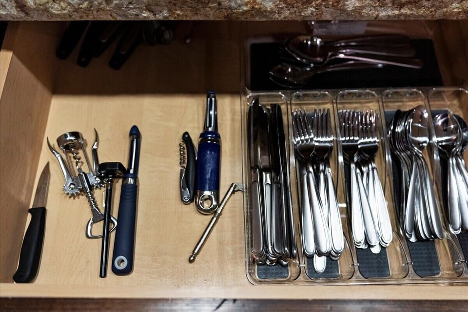 Kitchen utensil drawer with knives, corkscrews, forks, spoons, and serving utensils.