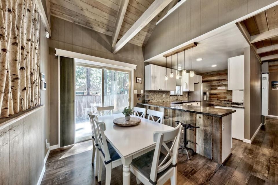 Dining area with table seating, counter stool, pendant lights, kitchen in view, and a vaulted ceiling.