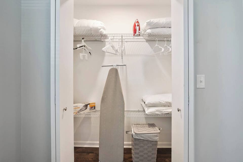 Large master closet, with an iron, ironing board, extra pillows, sheets, and a small hand vac.