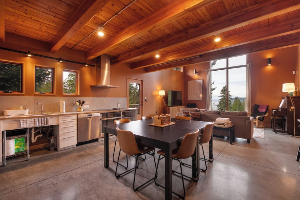 The open-concept kitchen and dining area, featuring wood beam ceilings, and seats six at the table and two at the nearby counter. 