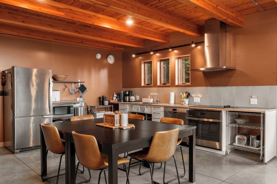 The open-concept kitchen and dining area, with wood beam ceilings and stainless steel appliances, are fully equipped to meet all your needs.