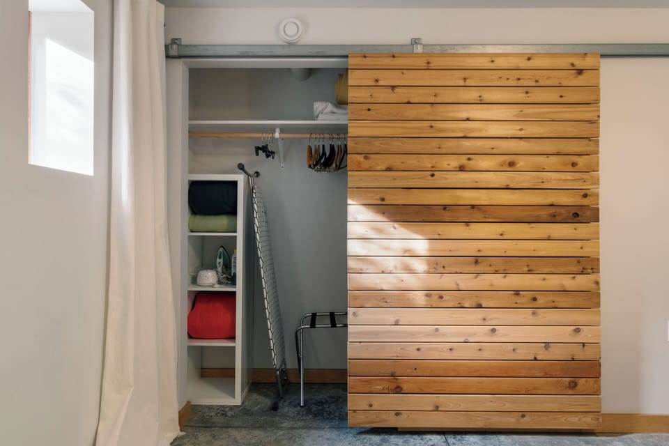 The spacious ground-floor bedroom features a large closet, with cubbies, shelving, plenty of hangers, extra blankets and pillows, an ironing board and iron, and a luggage rack. 