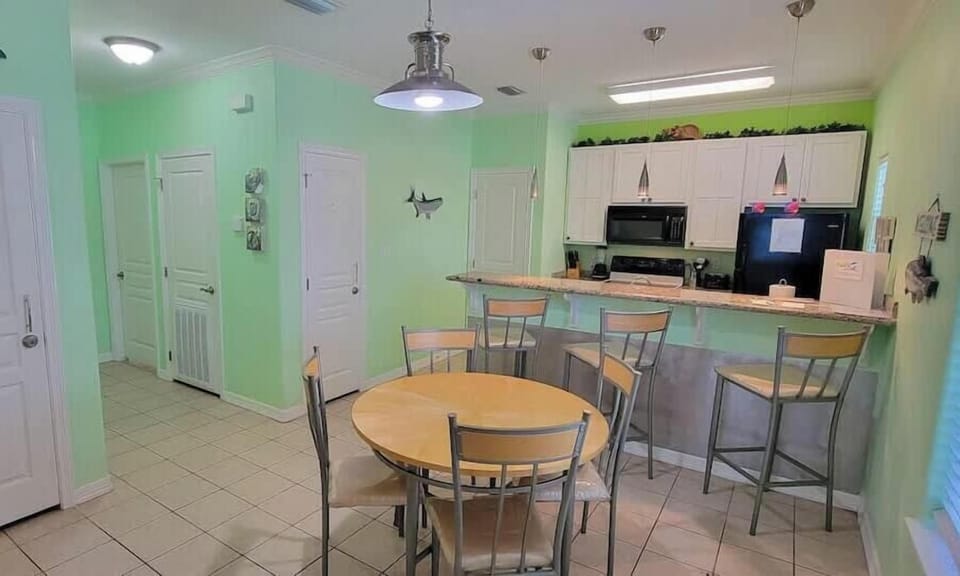 Enjoy meals in this inviting kitchen and dining area featuring a round table, breakfast bar with stools, white cabinetry, and modern appliances. Natural light and tasteful décor make it perfect for cooking, dining, and entertaining.