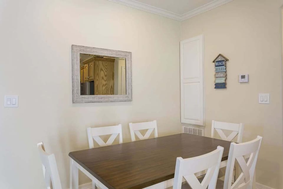 Bright Dining Space with Wooden Table, Cross‑Back Chairs & Warm Neutral Décor — Perfect for Shared Meals and Relaxed Gatherings