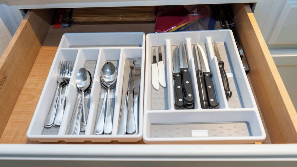 Fully stocked cutlery drawer with forks, spoons, knives, and a variety of prep knives—making every meal prep and dining experience easy and convenient in this comfortable coastal kitchen.