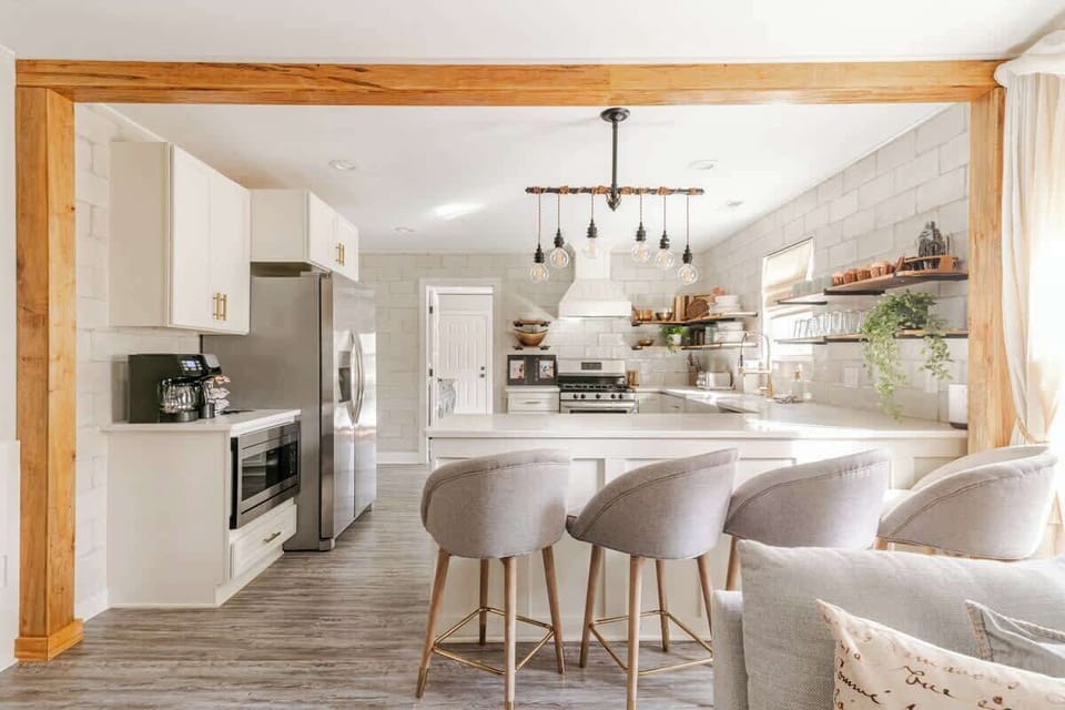 Bright, open Charlotte kitchen with a spacious quartz island, comfortable bar seating, stainless appliances, and designer lighting. A welcoming gathering space for cooking, sharing meals, and enjoying time together.