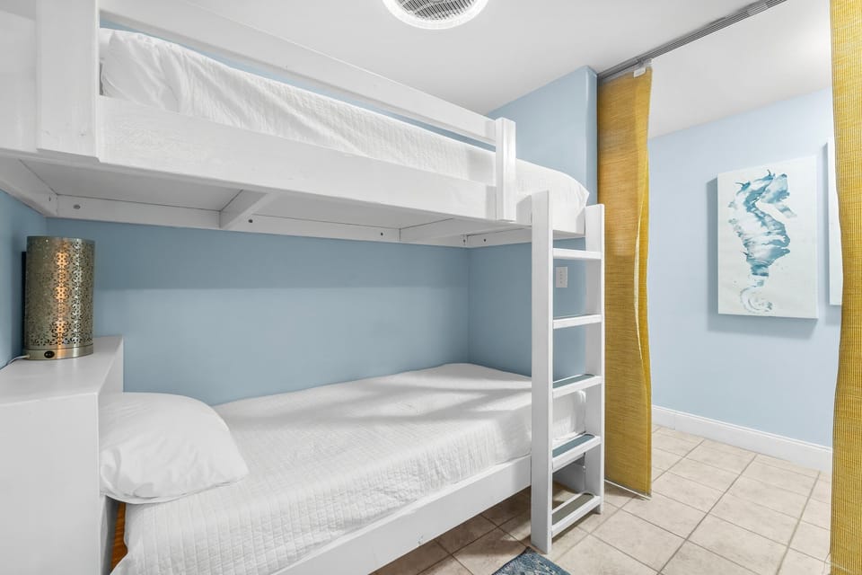 A clean bunk bed setup in a bright, simple room with light blue walls.