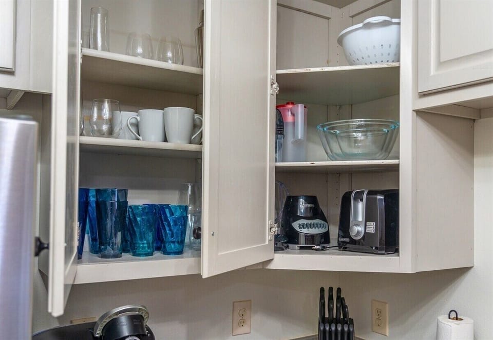 Open cabinets stocked with sparkling glassware and drink essentials ensure you have everything you need for a refreshing drink or a cozy evening in.