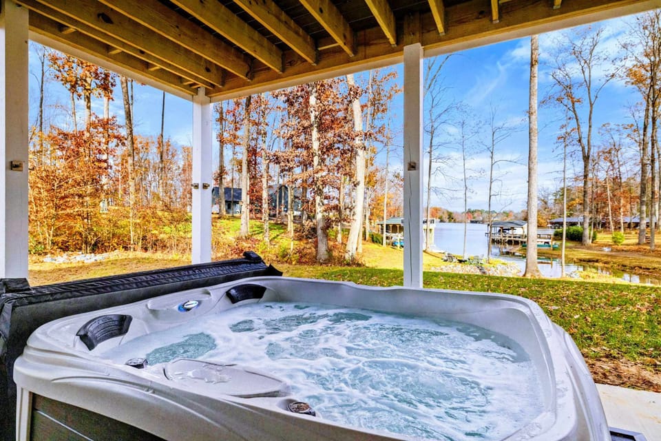 Relaxing hot tub on a covered patio with beautiful views of the lake and surrounding wooded area.