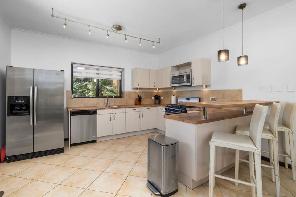 Modern kitchen with sleek appliances, a stylish wooden countertop, and a cozy bar seating area