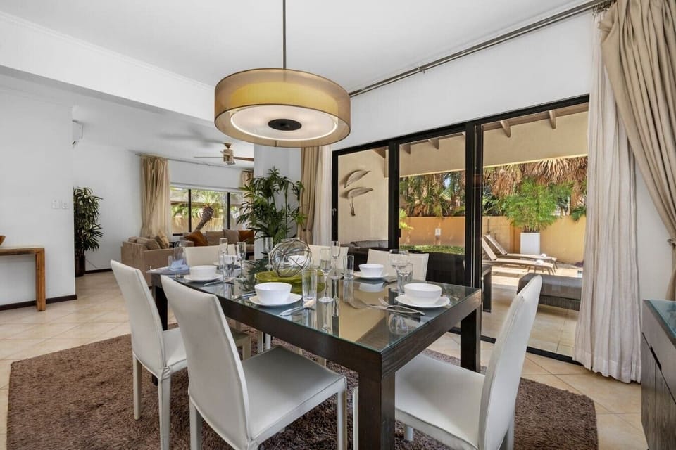 Bright dining area with a sleek glass table, modern chairs, and a view of the serene patio