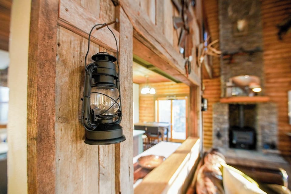 Rustic charm on display—an antique lantern mounted against reclaimed wood beams adds a nostalgic touch to this warm, cabin-inspired space.