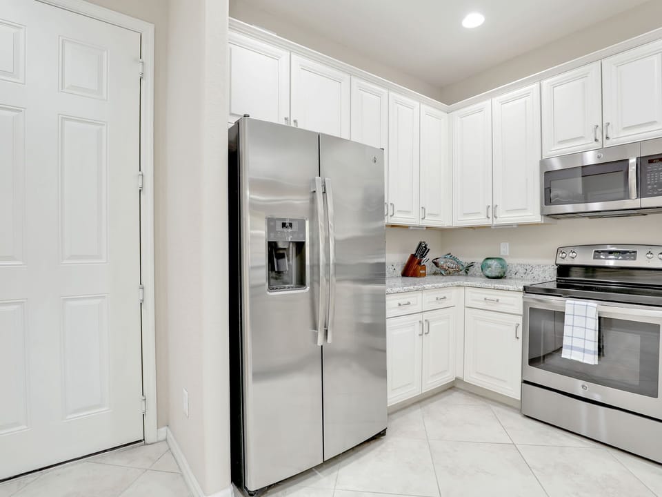 Modern kitchen corner featuring stainless steel appliances and white cabinetry.