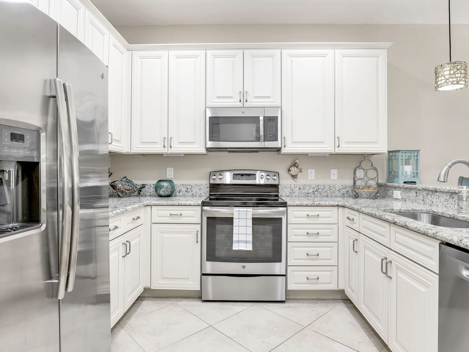 Modern kitchen with stainless steel appliances and white cabinetry.