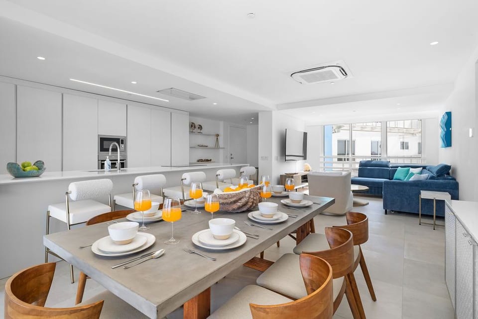 Gather around this bright, open dining area where fresh juice and breakfast await, then relax on the plush sofa—your perfect blend of comfort and style.