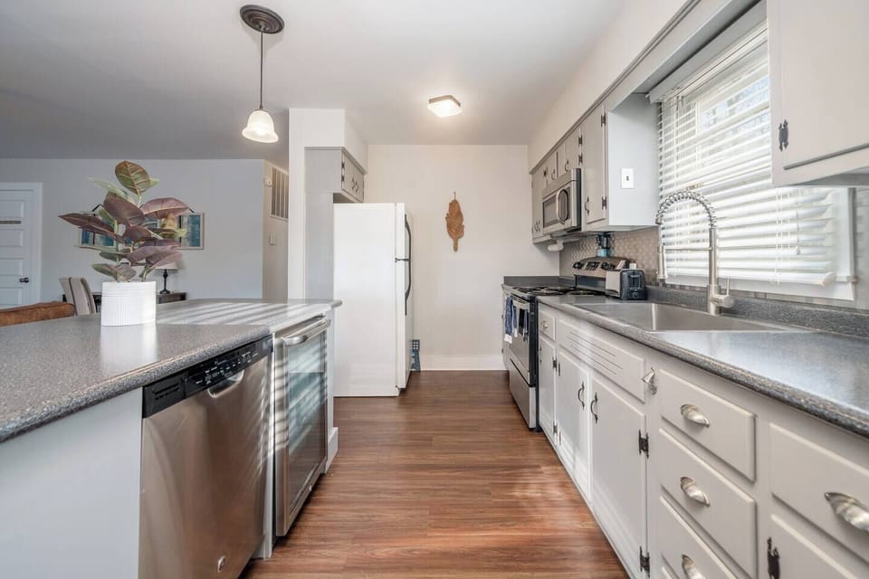 Spacious kitchen with electric stove, deep sink, refrigerator, dishwasher, and beverage sink. 