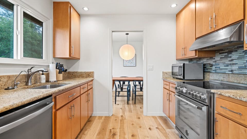 Kitchen equipped with electric stovetop, oven and small coffee bar.