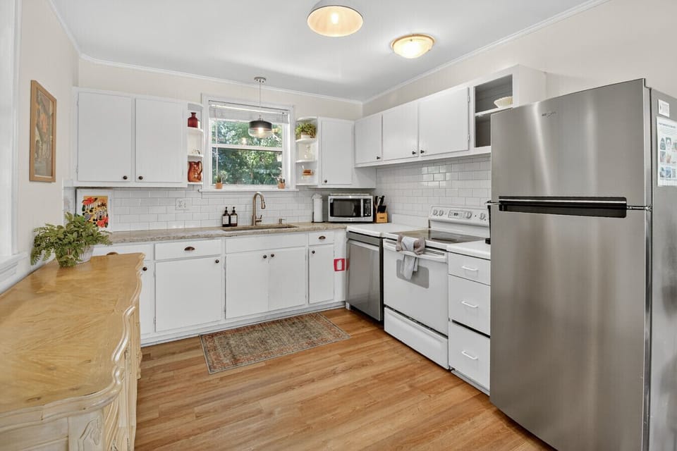 Cook and gather in a fully equipped kitchen with stainless steel appliances, open shelving, and warm natural light.