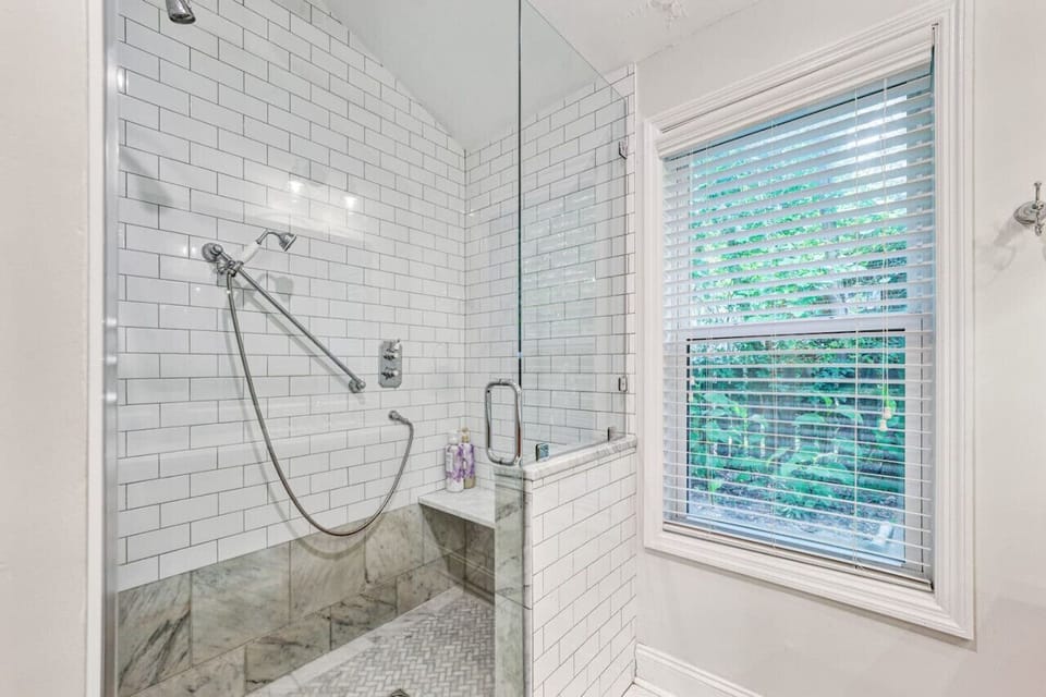 Dual vanity master bathroom. The waterfall shower features a detachable handle wand and a built-in marble seat.