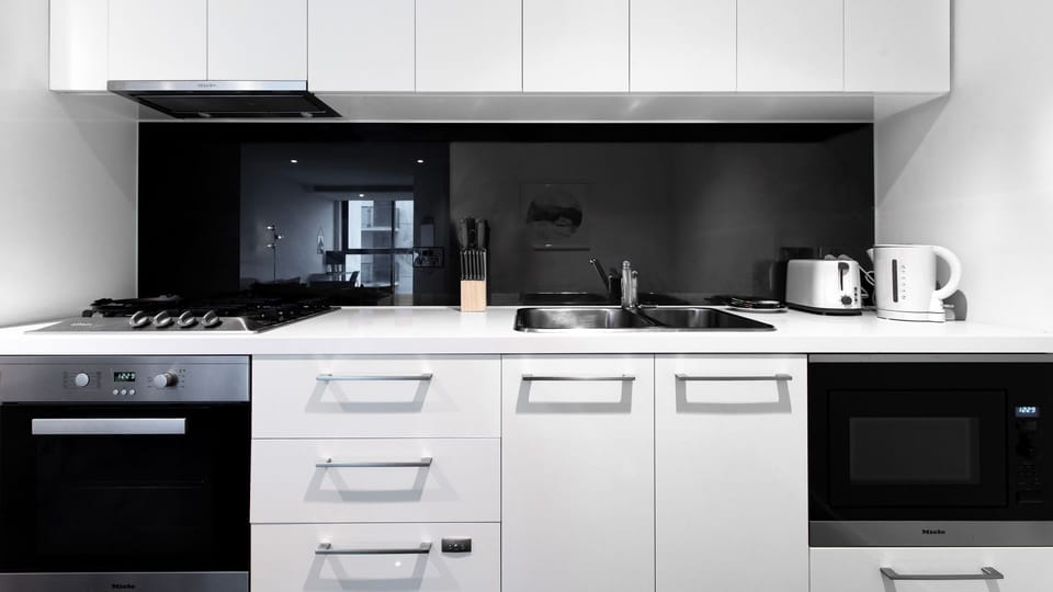 Channel your inner chef in this ultra-modern kitchen complete with sleek white cabinetry and a striking dark backsplash.