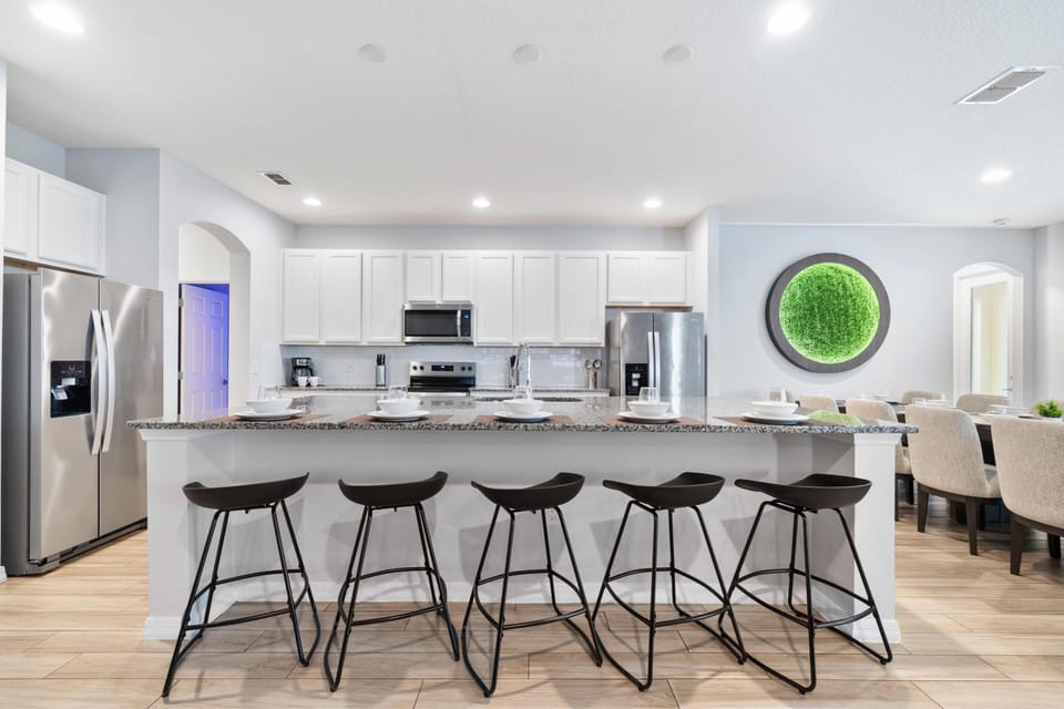 - Modern kitchen with granite countertops and bar stools  
- Stainless steel appliances and white cabinetry design  
- Vacation rental in Orlando with spacious cooking area