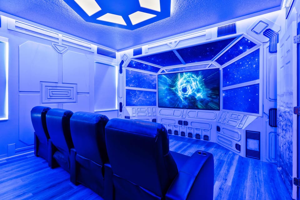 - Space themed home theater with glowing blue lighting  
- Recliner seats facing a large immersive cinema screen  
- Orlando vacation rental with private movie room fun