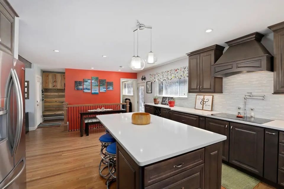 The kitchen has a large island with barstools or a dining table. 