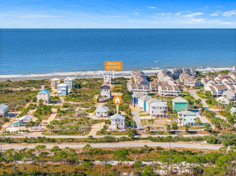Aerial view of a coastal community with beach houses and vacation rentals near pristine shoreline with convenient beach access.