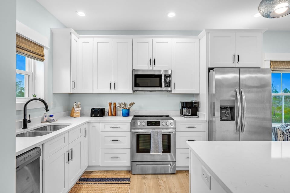 Whip up memorable meals in this bright, fully-equipped kitchen featuring stainless steel appliances and pristine white cabinetry.