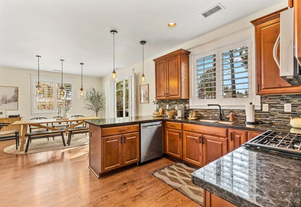 Dark countertops and wood cabinets create a stunning contrast in this modern kitchen, featuring stainless steel appliances and all the essentials.