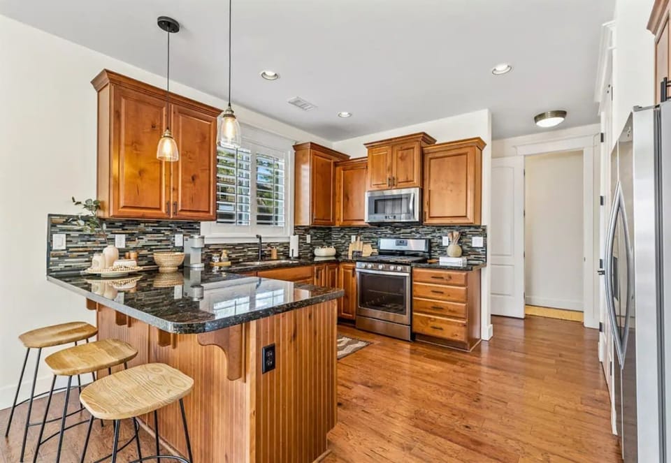 This sleek kitchen boasts dark countertops, wood cabinets, and stainless steel appliances for a stylish cooking space.