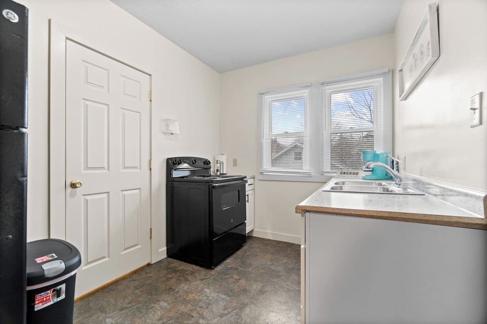 Modern full kitchen featuring a sleek sink with faucet, stylish cabinets, elegant granite countertops, a stove, and a window that lets in natural light—designed for both functionality and contemporary style, creating an inviting cooking space